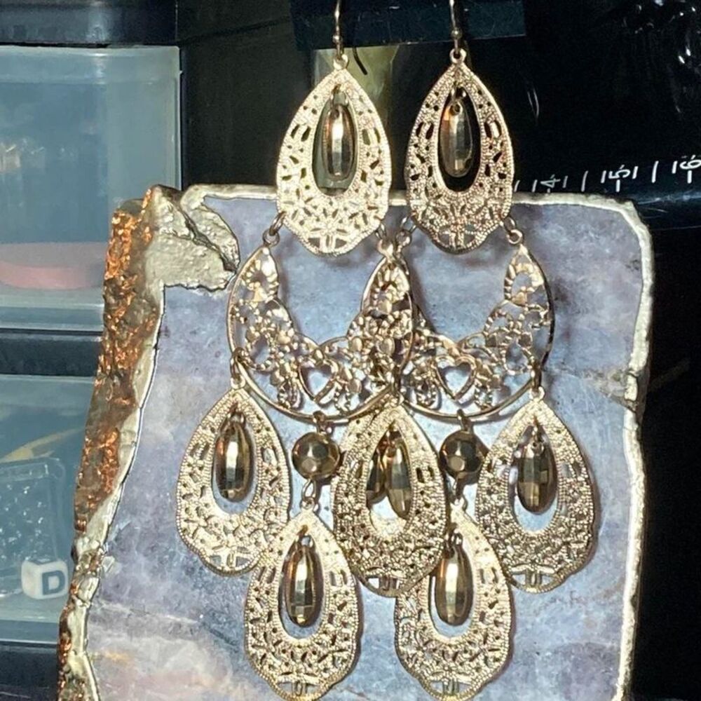 Gold ornate earrings with intricate filigree and teardrop-shaped beads